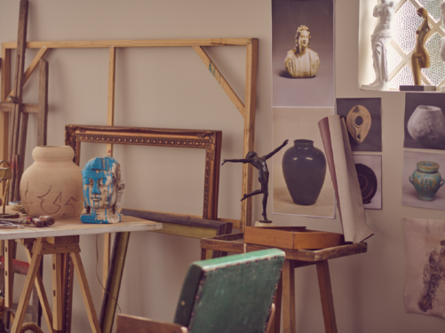 Fotografia de um estúdio de artes, com pinturas, esculturas e materiais diversos